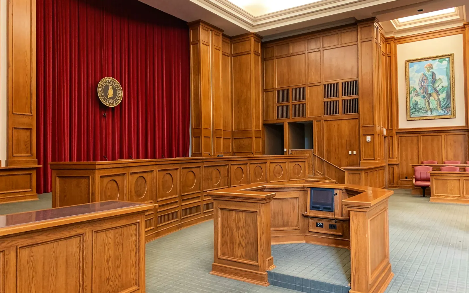 Empty wood-paneled courtroom with the judge’s bench and witness stand