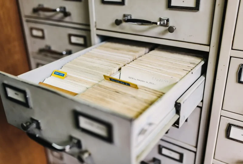 Open drawer of a metal filing cabinet filled with record cards