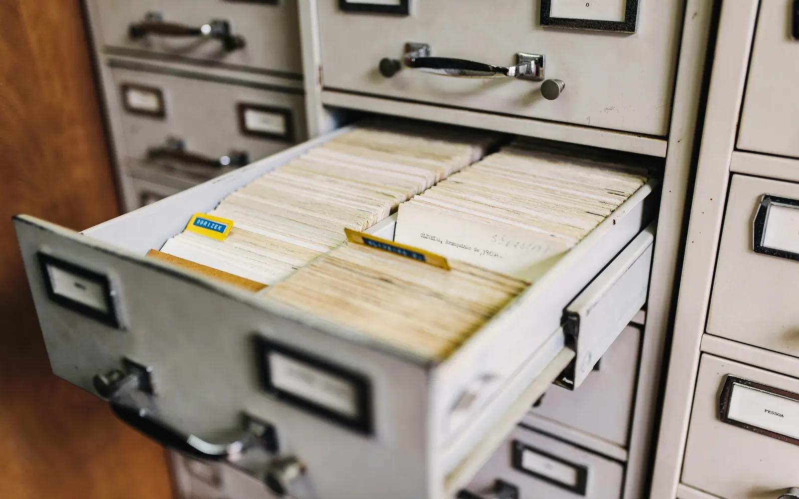 Open drawer of a metal filing cabinet filled with record cards