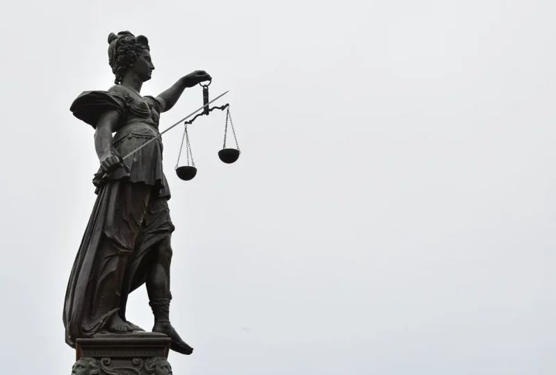 Statue of Lady Justice holding scales against an overcast sky