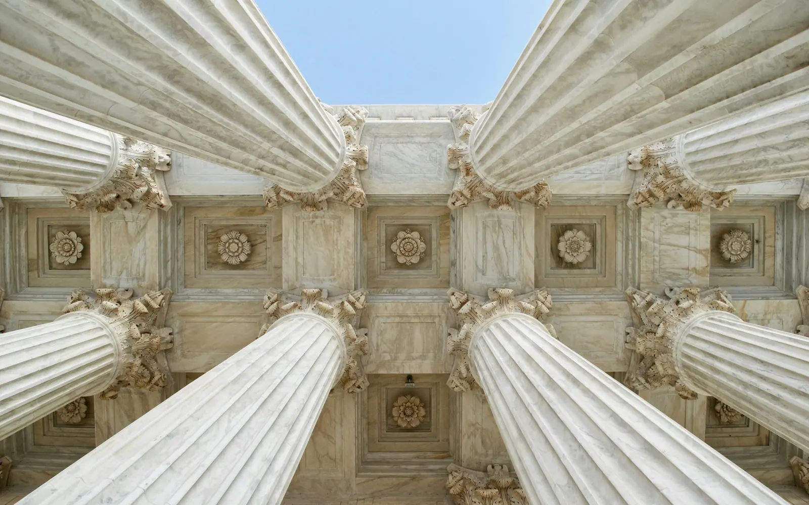 Stone columns and a carved ceiling of a classical building, viewed from below